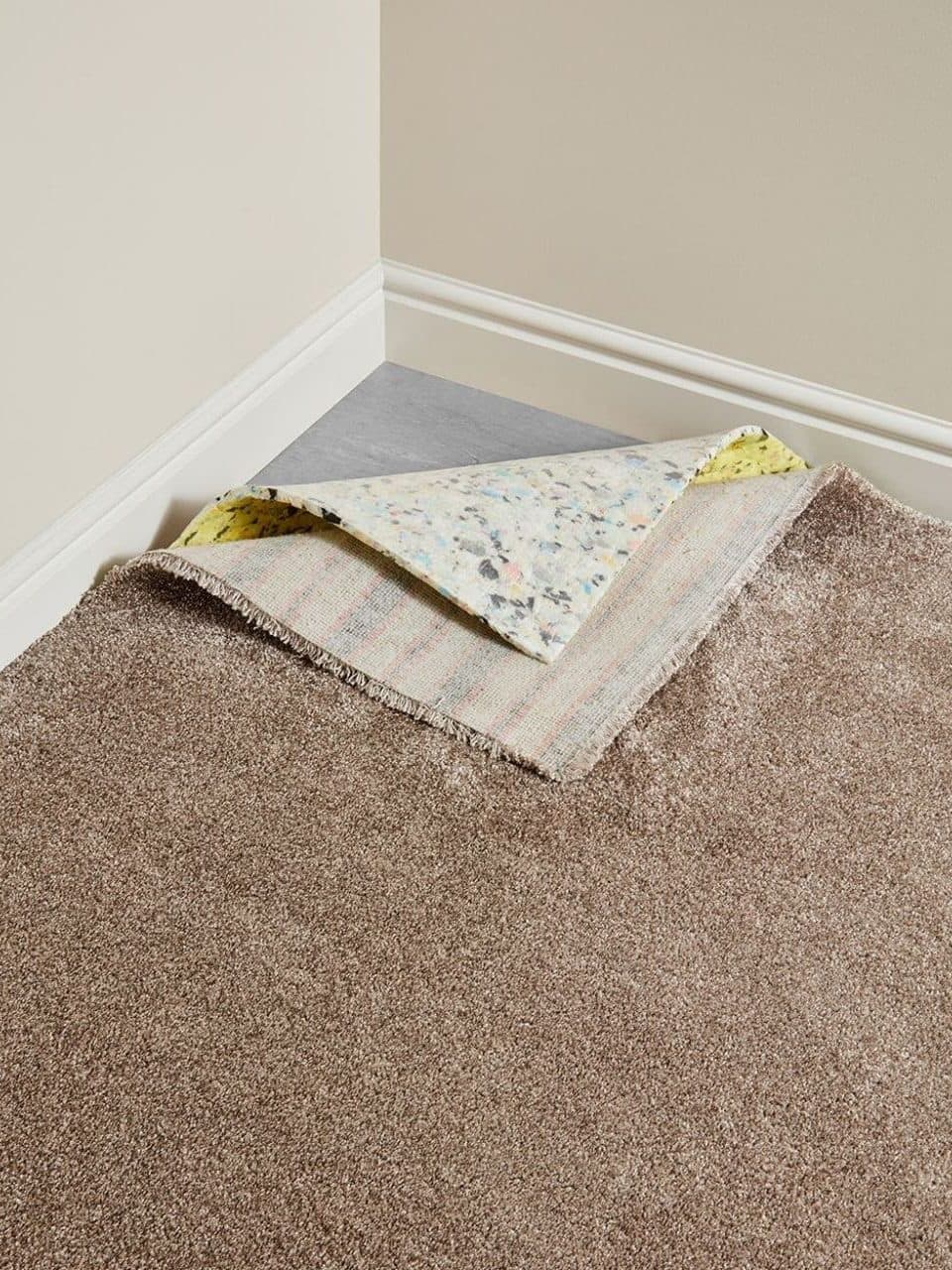 Wall to wall carpet being laid, with the underlay layers folded back at the skirting